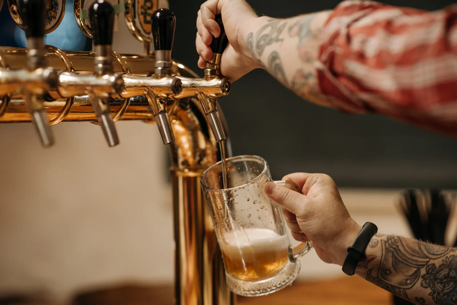 Close-up of a landlord pulling a pint from a brass tap